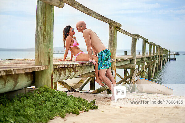 Affectionate boyfriend and girlfriend on wooden beach pier