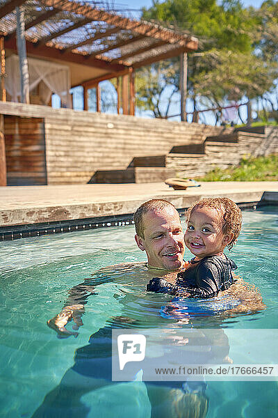 Portrait happy father and toddler son in swimming pool