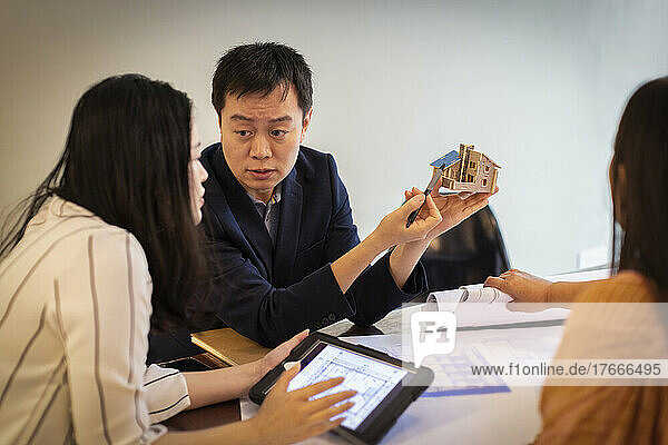 Architects looking at house model in conference room meeting