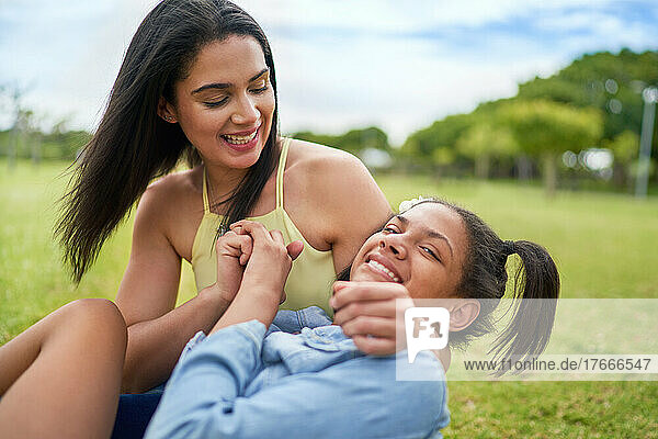 Portrait happy mother and disabled daughter laying n park grass