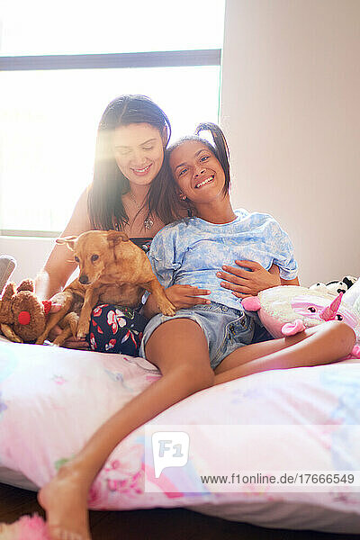 Portrait happy disabled daughter with mother and dog on bed