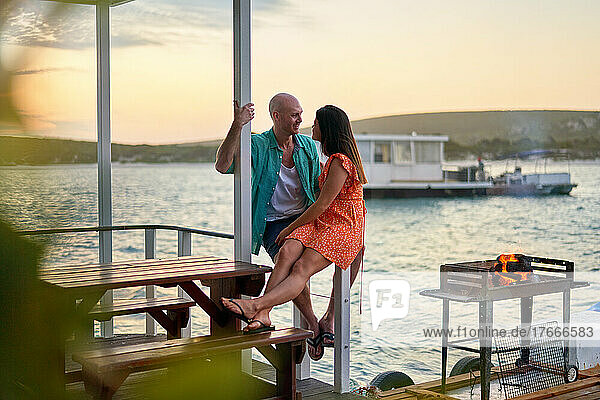 Happy couple relaxing and talking on houseboat patio on lake