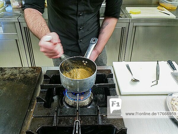 Chef using a hand mixer making a potato sauce cream reduction in a professional kitchen of a restaurant  gourmet professional cooking concept