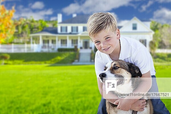 Glücklicher Junge und sein Hund im Vorgarten ihres Hauses
