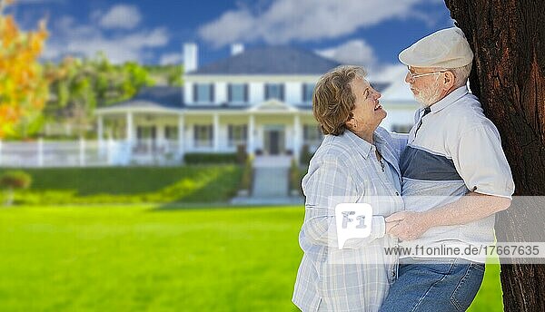 Glückliches Seniorenpaar im Vorgarten seines Hauses