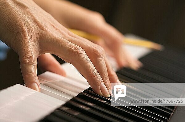 Finger einer Frau mit Bleistift auf den Tasten eines Digitalpianos
