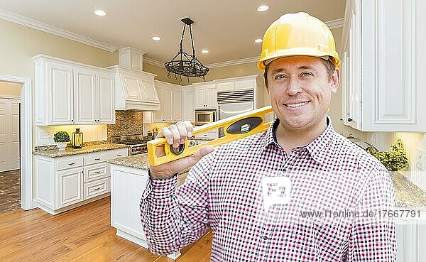 Smiling contractor with level wearing hard hat standing in custom kitchen