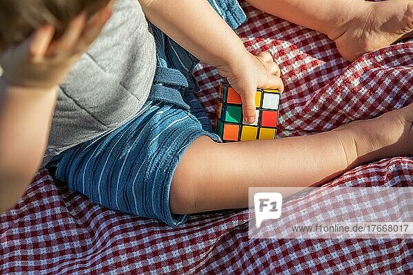 Baby boy sitting on picnic blanket playing with cube puzzle
