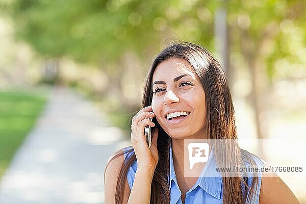 Schöne junge ethnische Frau  die draußen mit ihrem Smartphone spricht