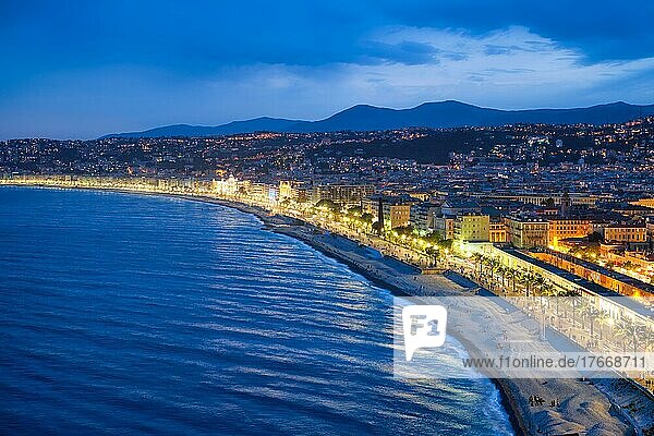 Scenic view of Nice  France in evening blue hour  Mediterranean Sea waves surging on coast  people relaxing on beach  lights illumination on colorful houses