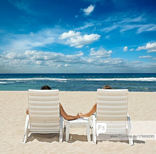 Paar in Strandstühlen hält Hände in der Nähe von Meer