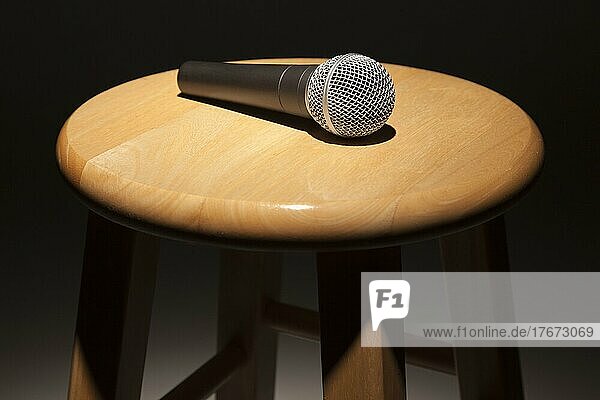 Microphone laying on wooden stool under spotlight abstract