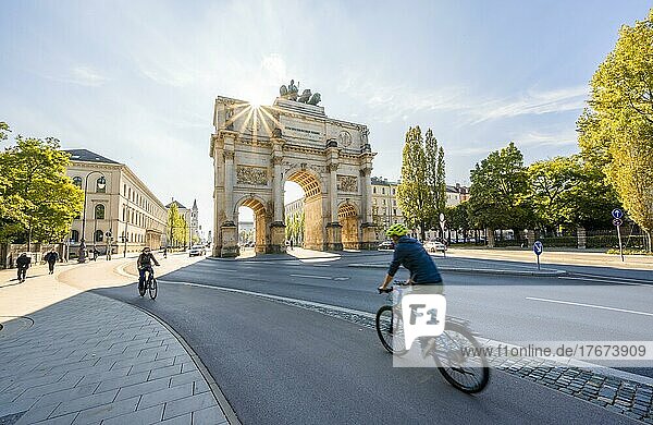 Sonnenstern  Siegestor  Fahrradfahrer fahren an der Leopoldstraße  Neoklassizistische Architektur  Bayern  München  Bayern  Deutschland  Europa
