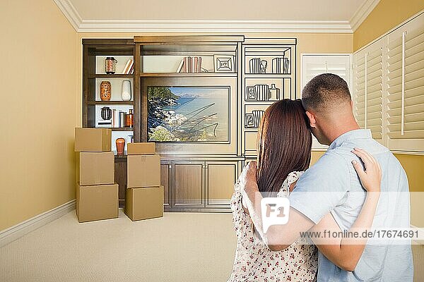 Young military couple looking at drawing of entertainment unit in room with moving boxes