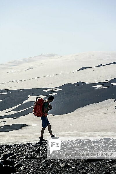 Wanderer auf Wanderweg  Karge hügelige Vulkanlandschaft aus Schnee und Lavafeldern  hinten Gletscher Eyjafjallajökull  Wanderweg Fimmvörðuháls  Þórsmörk Nature Reserve  Suðurland  Island  Europa