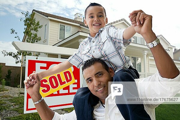 Hispanischer Vater und Sohn vor ihrem neuen Haus mit dem Schild Haus zu verkaufen