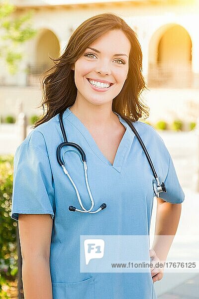 Portrait of young adult female doctor or nurse wearing scrubs and stethoscope outside