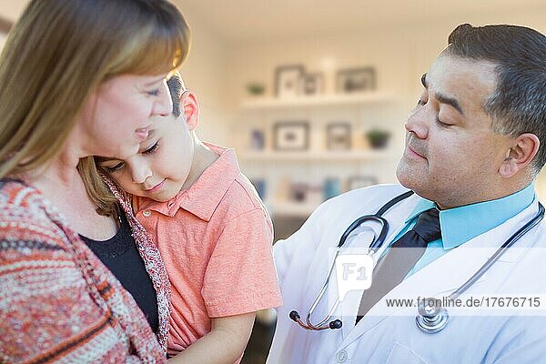 Young sick boy and mother visiting with hispanic doctor in office