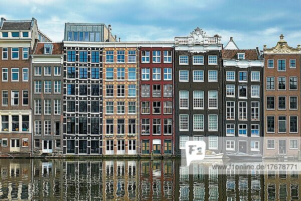 Row of typical houses and boat on Amsterdam canal Damrak with reflection. Amsterdam  Netherlands