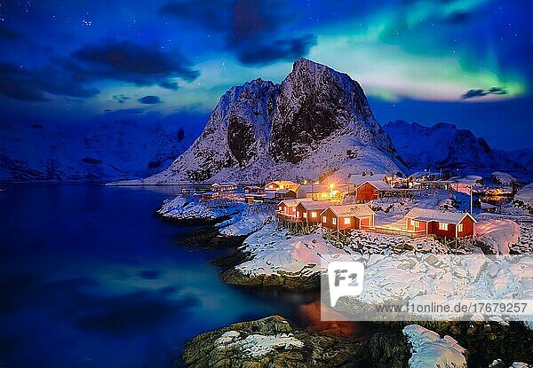 Berühmte Touristenattraktion Hamnoy  Fischerdorf auf den Lofoten  Norwegen  mit roten Rorbu-Häusern im Winterschnee  abends mit Aurora Borealis beleuchtet  Europa