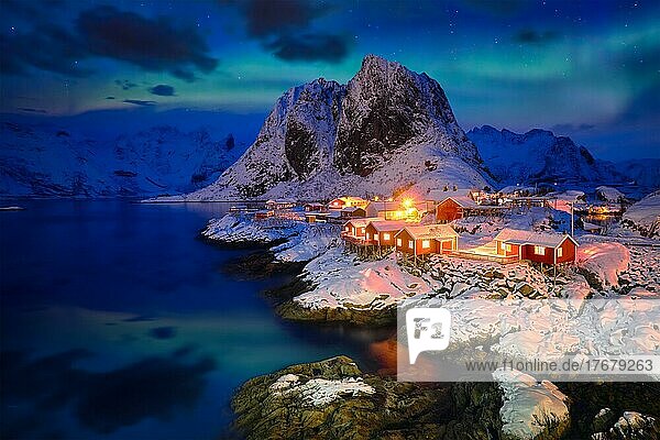 Berühmte Touristenattraktion Hamnoy  Fischerdorf auf den Lofoten  Norwegen  mit roten Rorbu-Häusern im Winterschnee  abends mit Aurora Borealis beleuchtet  Europa
