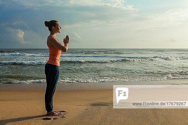 Woman doing Ashtanga Vinyasa Yoga asana Tadasana Samasthiti yoga posture on beach