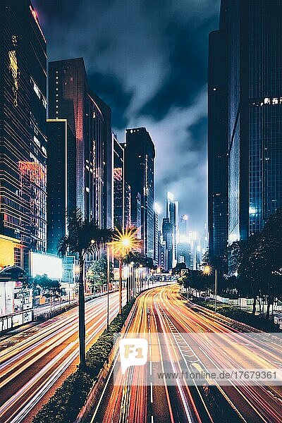 Straßenverkehr in Hongkong bei Nacht. Büro-Wolkenkratzer Gebäude und reger Verkehr auf der Autobahn Straße mit unscharfen Autos Lichtspuren. Hongkong  China  Asien