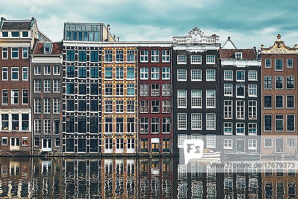 Row of typical houses and boat on Amsterdam canal Damrak with reflection. Amsterdam  Netherlands