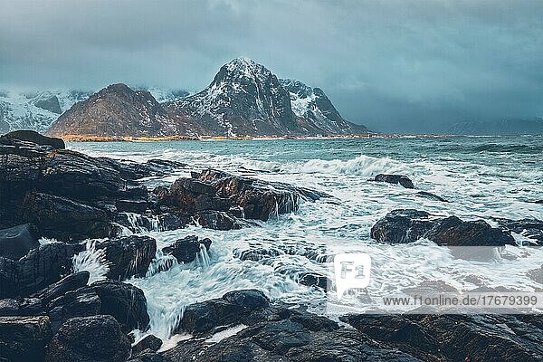 Wellen  die an Felsen an der felsigen Küste eines Fjords im norwegischen Meer im Winter zerschellen. Lofoten Inseln  Norwegen  Europa