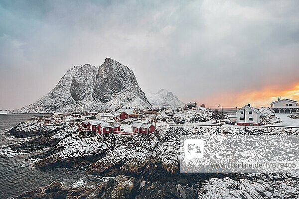 Berühmte Touristenattraktion Hamnoy Fischerdorf auf den Lofoten  Norwegen mit roten Rorbu-Häusern. Mit fallendem Schnee im Winter bei Sonnenaufgang