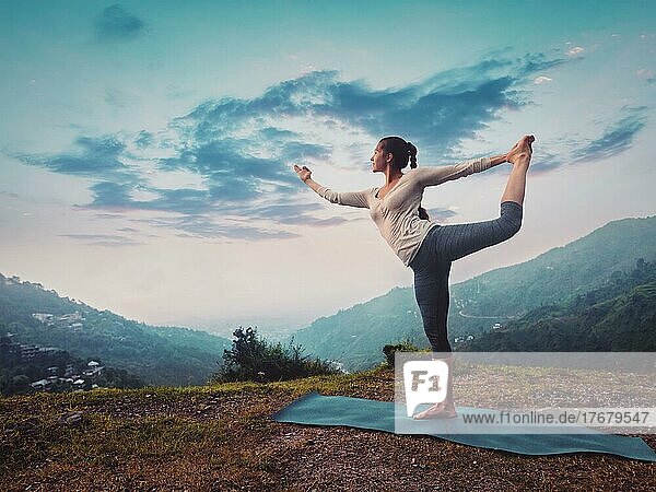 Woman doing yoga asana Natarajasana  Lord of the dance pose outdoors on sunset in Himalayas. Vintage retro effect filtered hipster style image