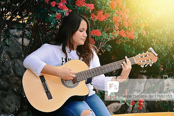 Porträt eines lächelnden Mädchens  das Gitarre spielt  Ein Mädchen  das im Freien Gitarre spielt  Lebensstil eines Mädchens
