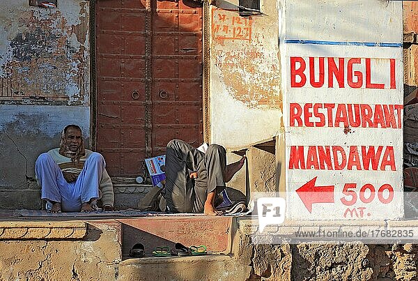 Rajasthan  Mandawa  Straßenszene im Zentrum der Kleinstadt  Hinweisschild zu einem Restaurant  Männer liegen und sitzen am Boden  Nordindien  Indien  Asien