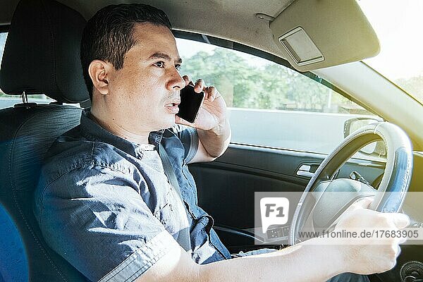 Concept of man calling on the phone while driving  A man driver calling on the phone in his car  Close up of a young man sitting inside car using mobile phone