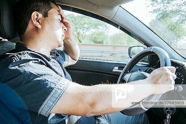 Fatigued driver stuck in traffic  concept of a fatigued man in his car  stressed. A driver with a headache in traffic  A person with a headache in traffic