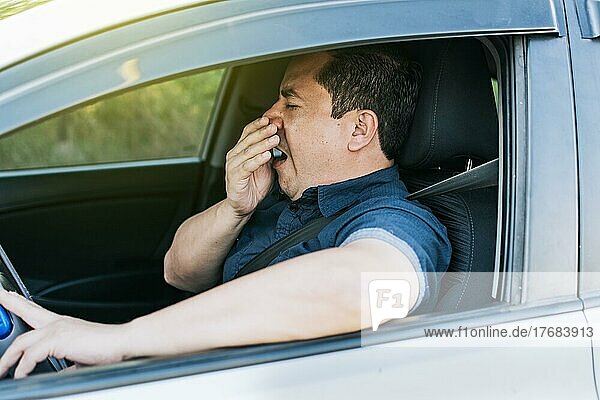 Tired driver yawning  concept of man yawning while driving. A sleepy driver at the wheel  a tired person while driving