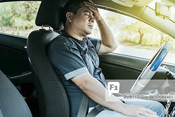 Eine Person im Auto mit Kopfschmerzen  Konzept eines Mannes in seinem Auto mit Kopfschmerzen  Ein Autofahrer mit Kopfschmerzen  Ein Fahrer mit Stress und Migräne