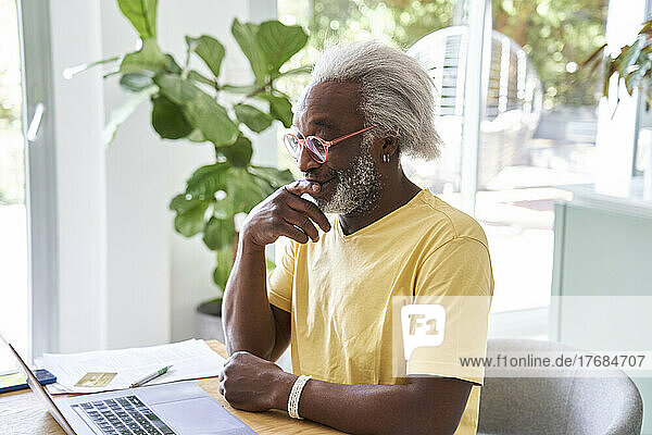 Senior man reflecting in front of his laptop