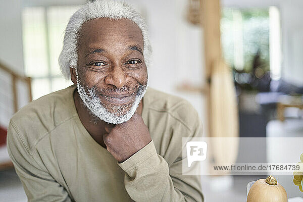 Smiling senior man leaning on kitchen worktop