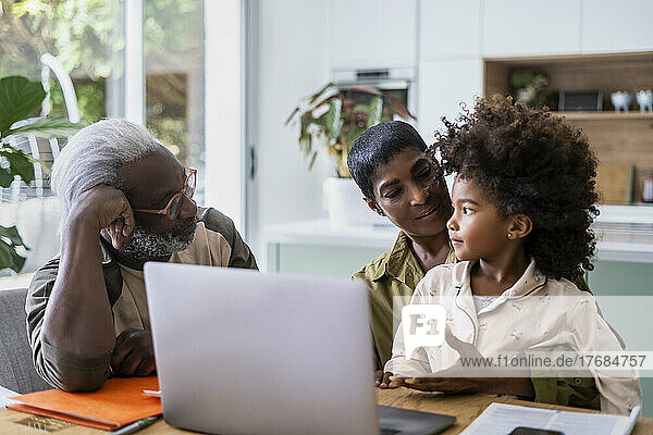 Grandparents with granddaughter using laptop