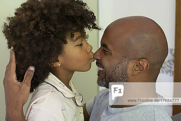 Daughter kissing his father's nose and looking at each other