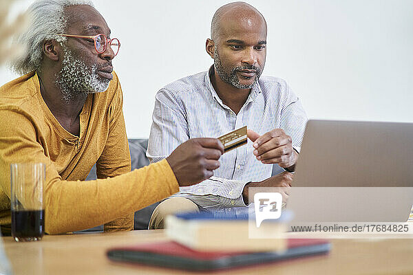 Father and son using laptop and credit card