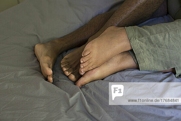 Feet of young couple lying on bed