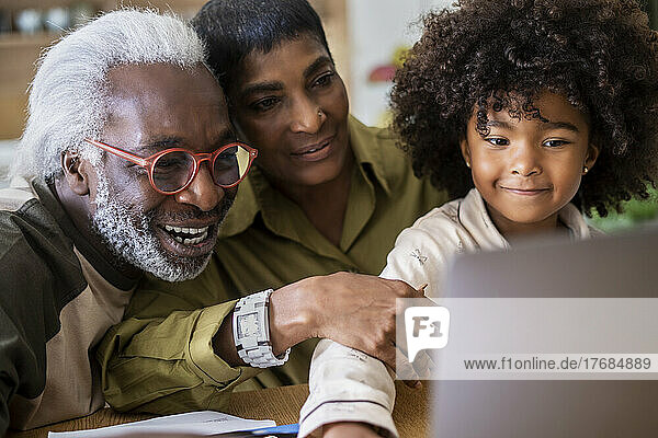 Grandparents with granddaughter using laptop