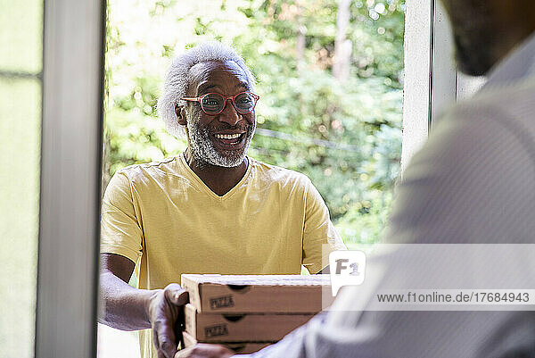 Senior deliveryman delivering pizza to man at doorstep