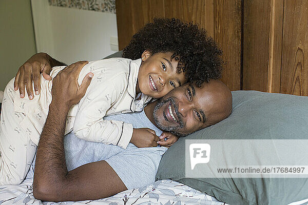 Smiling father and daughter relaxing on bed