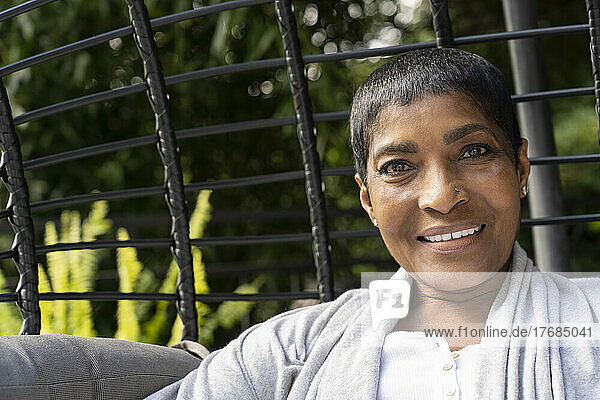 Smiling mature woman sitting on swing chair