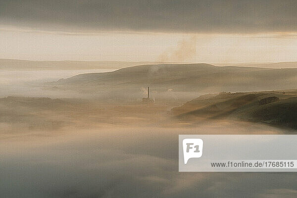 Smokestack in tranquil  sunny  foggy landscape at sunrise  Castleton  Derbyshire  England