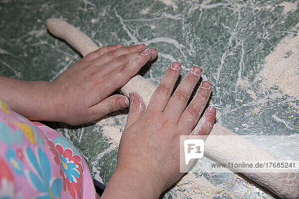 Close up view from above hands of girl rolling dough  baking on counter