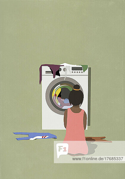 Woman watching laundry dry in clothes dryer